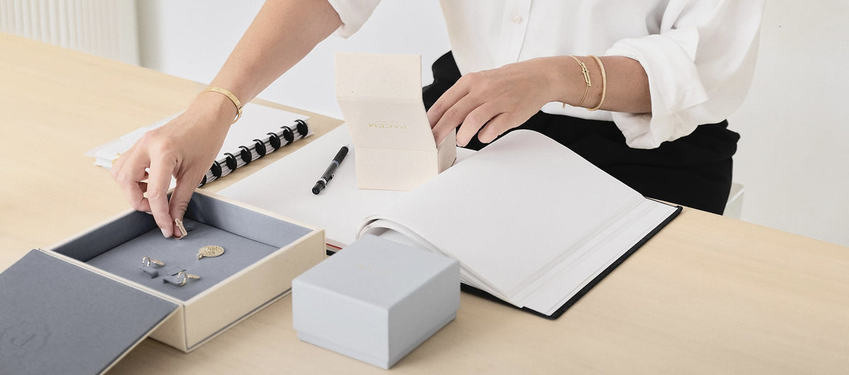 Pacem jewelry boxes, sketchbook and pieces laid out on a studio desk